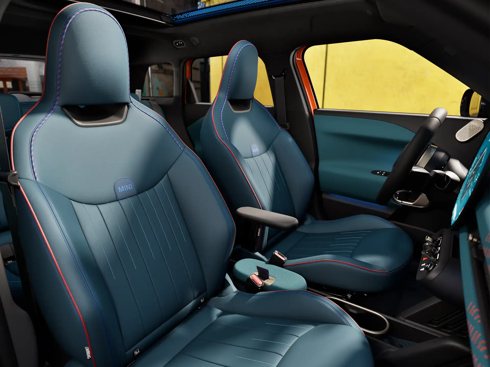 Innenansicht des vollelektrischen MINI Aceman zeigt das Armaturenbrett, das Lenkrad, das runde Display, das Panorama-Glasdach und die Rückseite der Vordersitze.