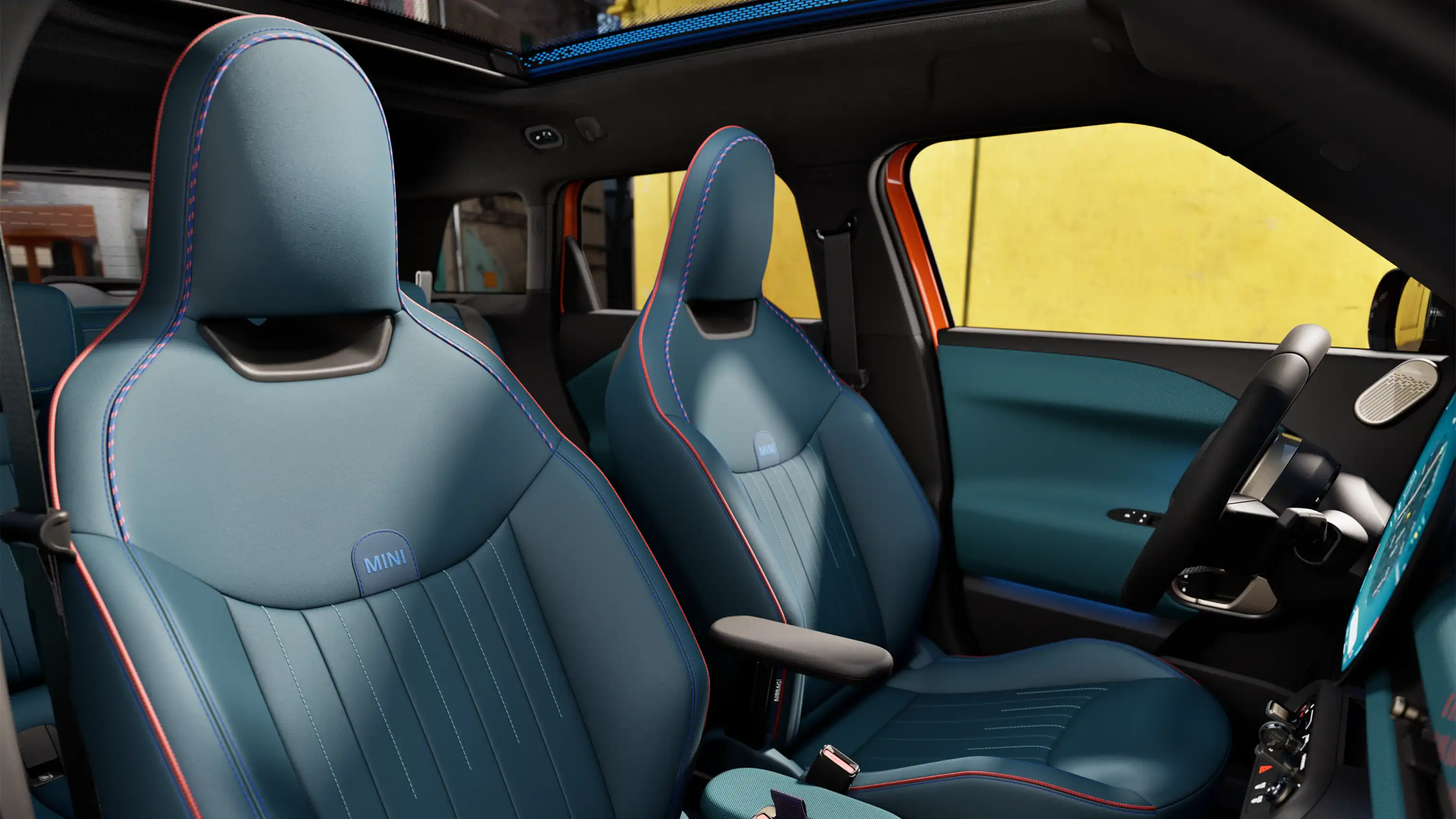 Innenansicht des vollelektrischen MINI Aceman zeigt das Armaturenbrett, das Lenkrad, das runde Display, das Panorama-Glasdach und die Rückseite der Vordersitze.