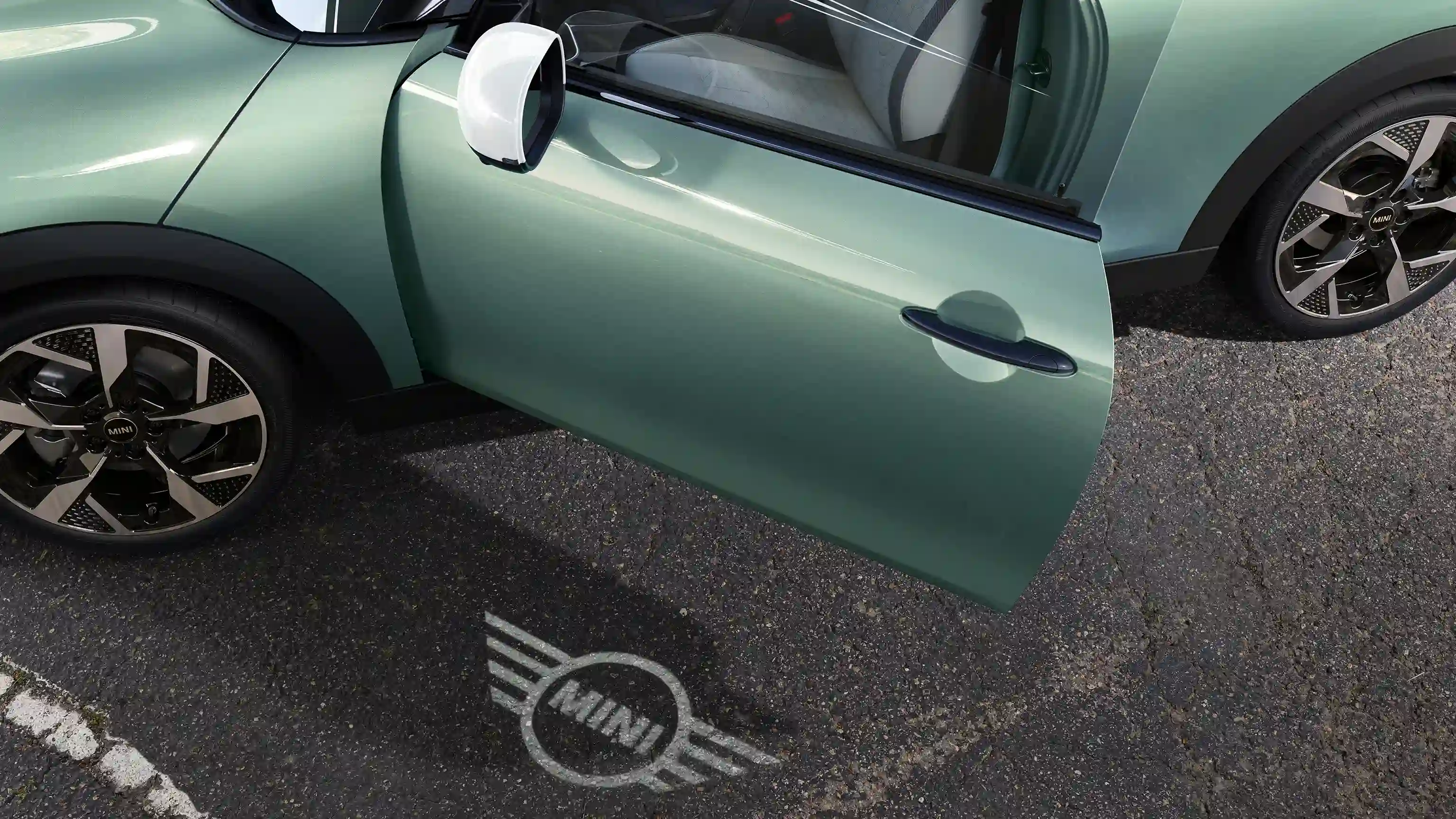 Außenansicht des MINI Cooper mit geöffneter Tür und Begrüßungslicht mit MINI Logo auf dem Boden 