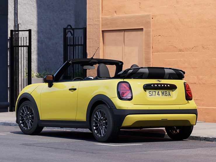 Ansicht von hinten links auf ein geparktes MINI Cooper Cabrio in Sunnyside Yellow.