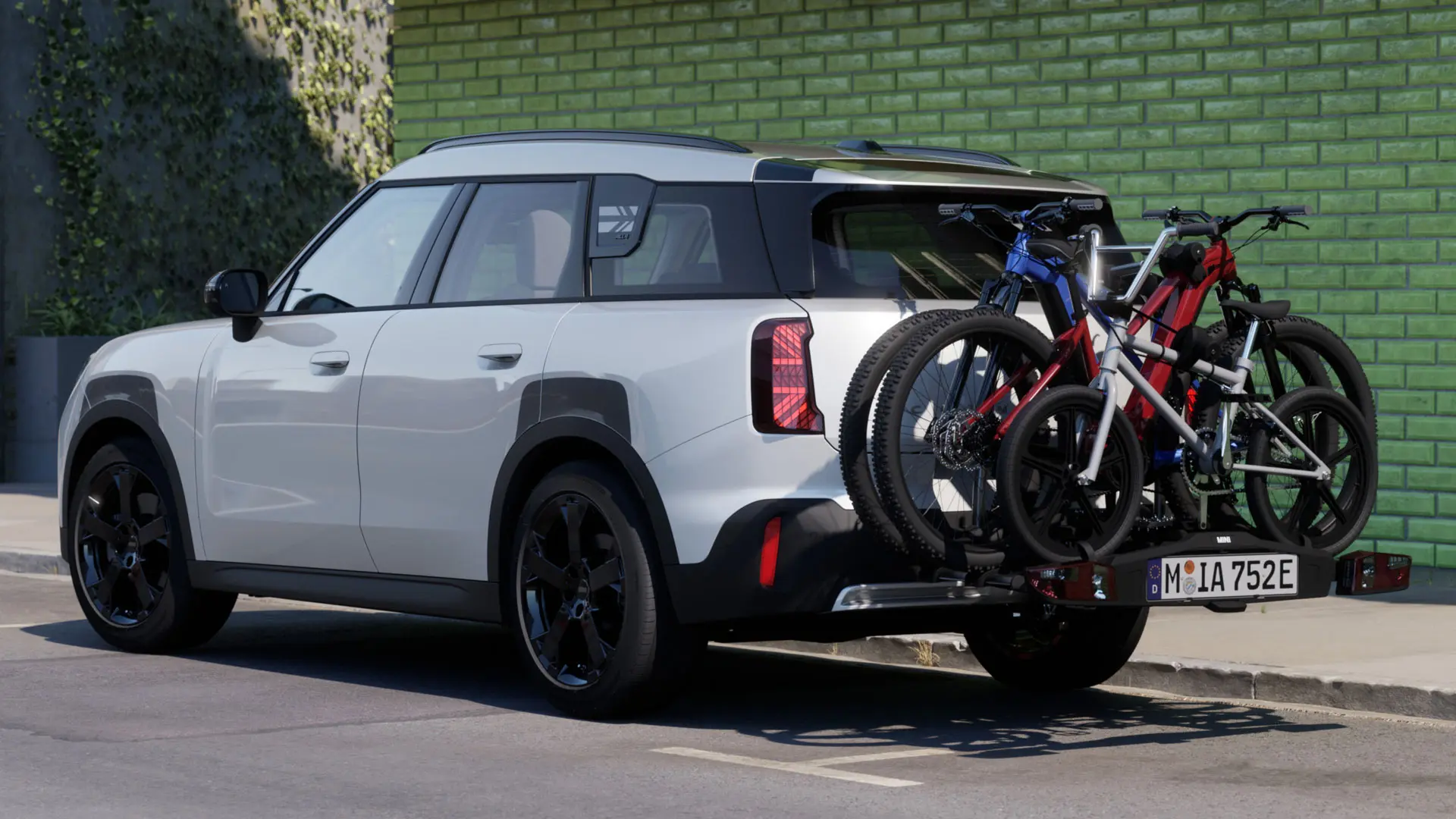Ein MINI Aceman in Nanuq White mit MINI Fahrradheckträger Pro 3.0, auf dem zwei Mountainbikes und ein Kinderfahrrad befestigt sind.