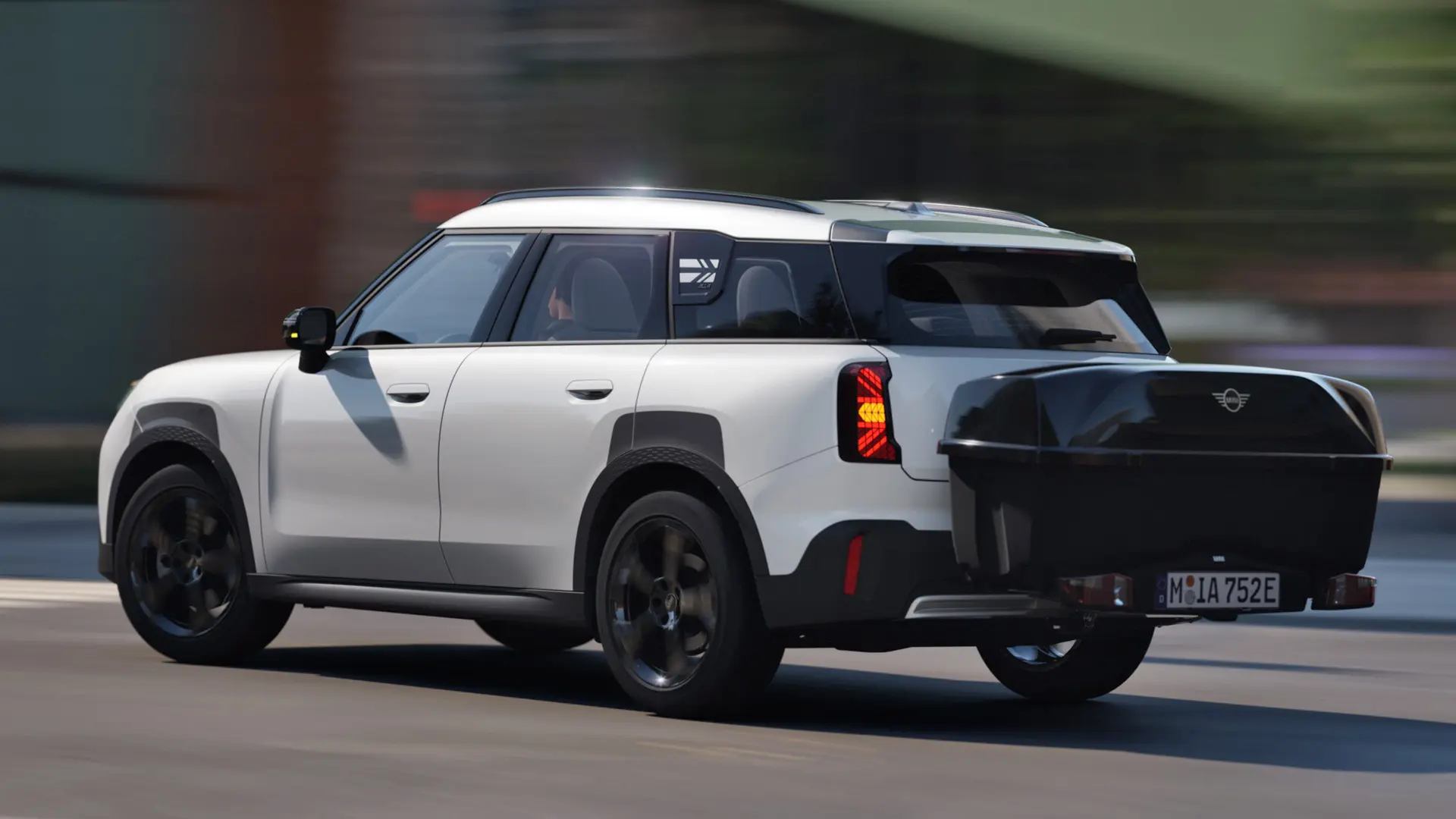 Heckansicht eines MINI Aceman in Nanuq White, der mit einem MINI Fahrradheckträger ausgestattet ist, auf dem die MINI Heckbox montiert ist. 