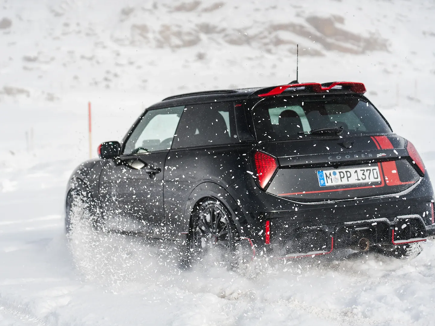 Ansicht von hinten auf einen MINI Cooper JCW, der durch den Schnee fährt
