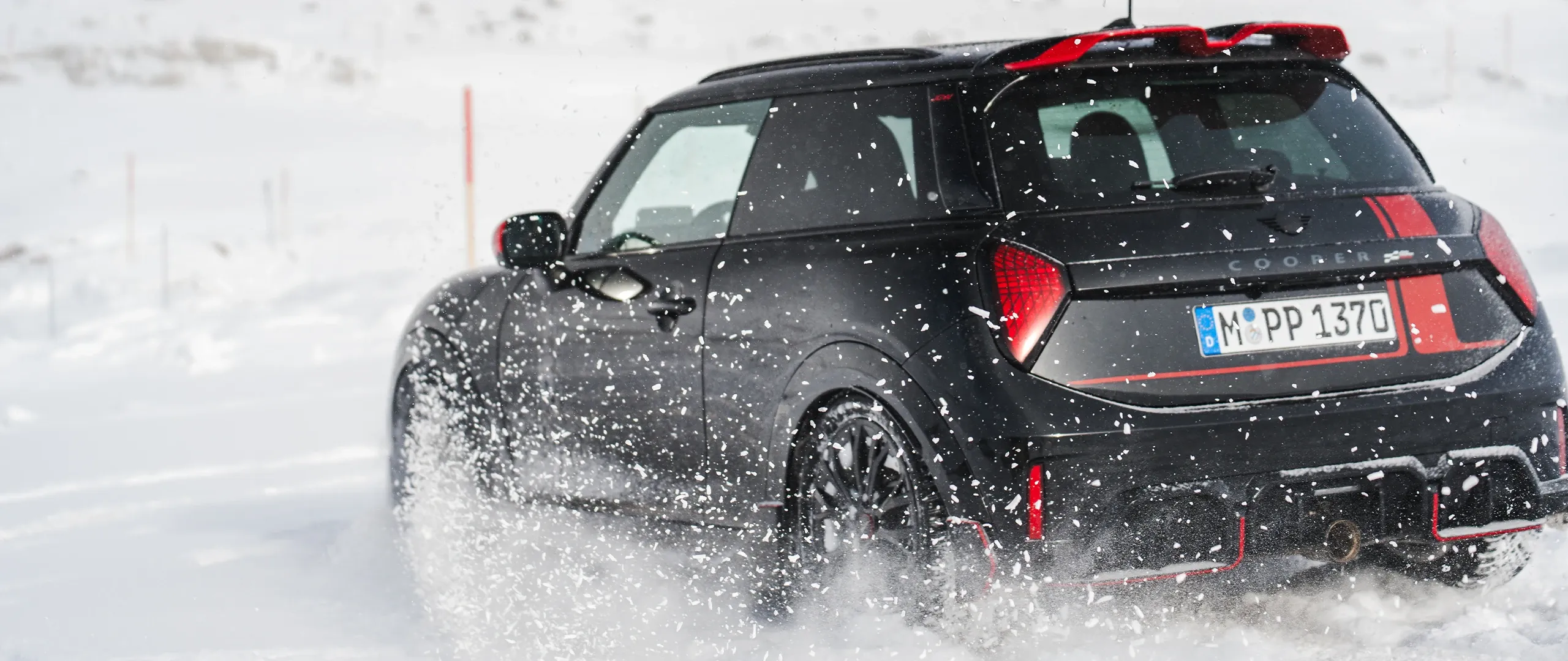 Ansicht von hinten auf einen MINI Cooper JCW, der durch den Schnee fährt