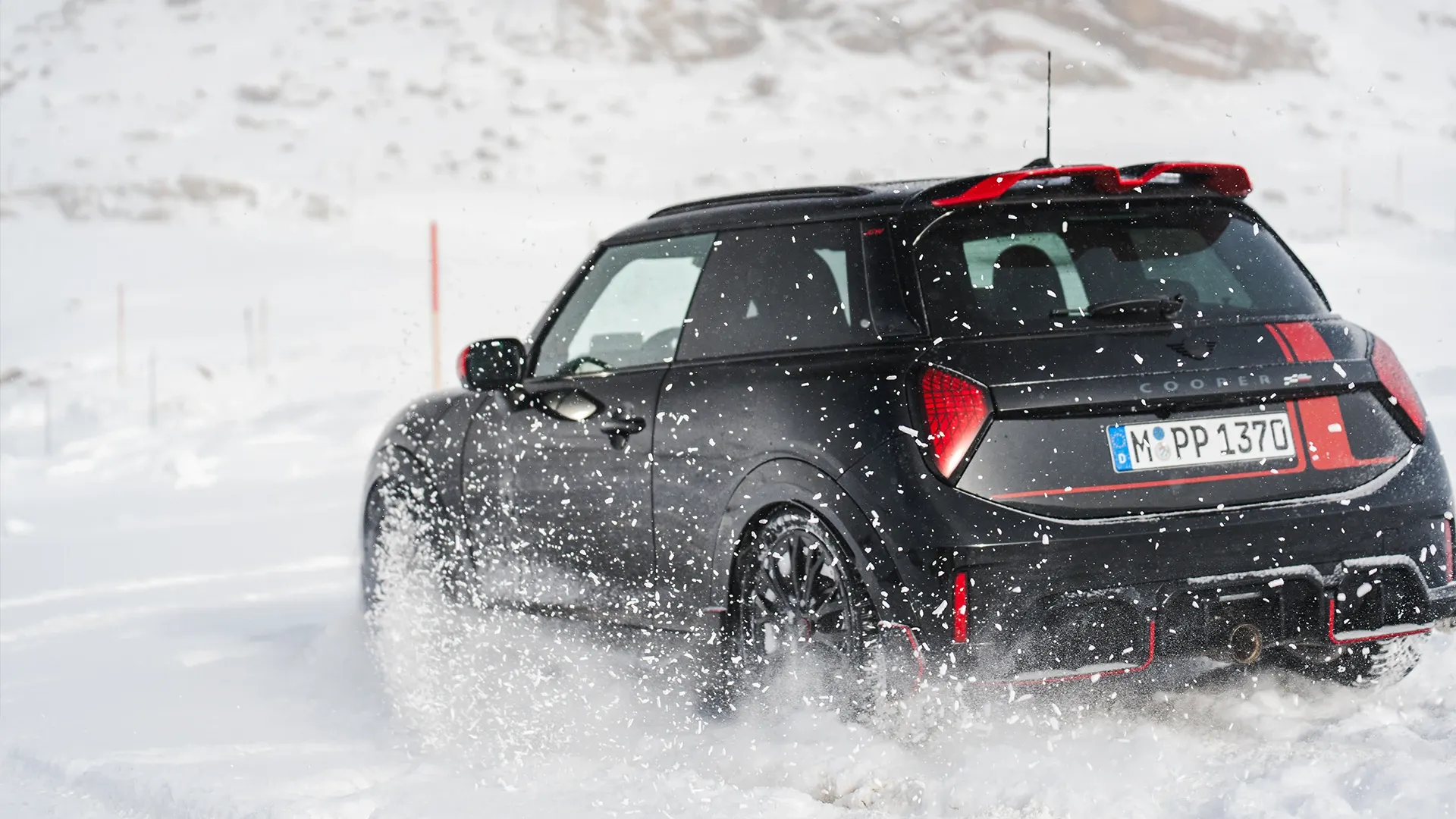 Ansicht von hinten auf einen MINI Cooper JCW, der durch den Schnee fährt