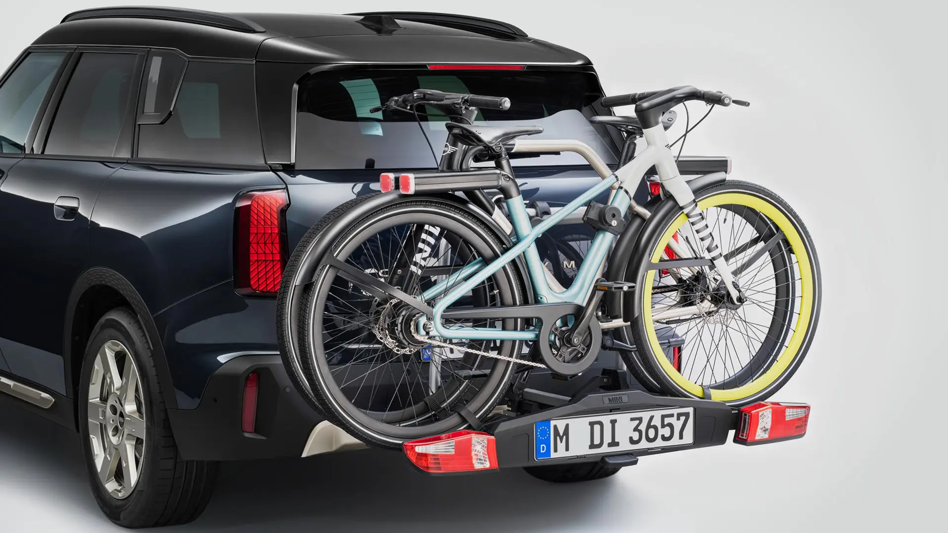Heckansicht eines MINI Countryman in Schwarz mit Fahrradheckträger und zwei Mountainbikes.