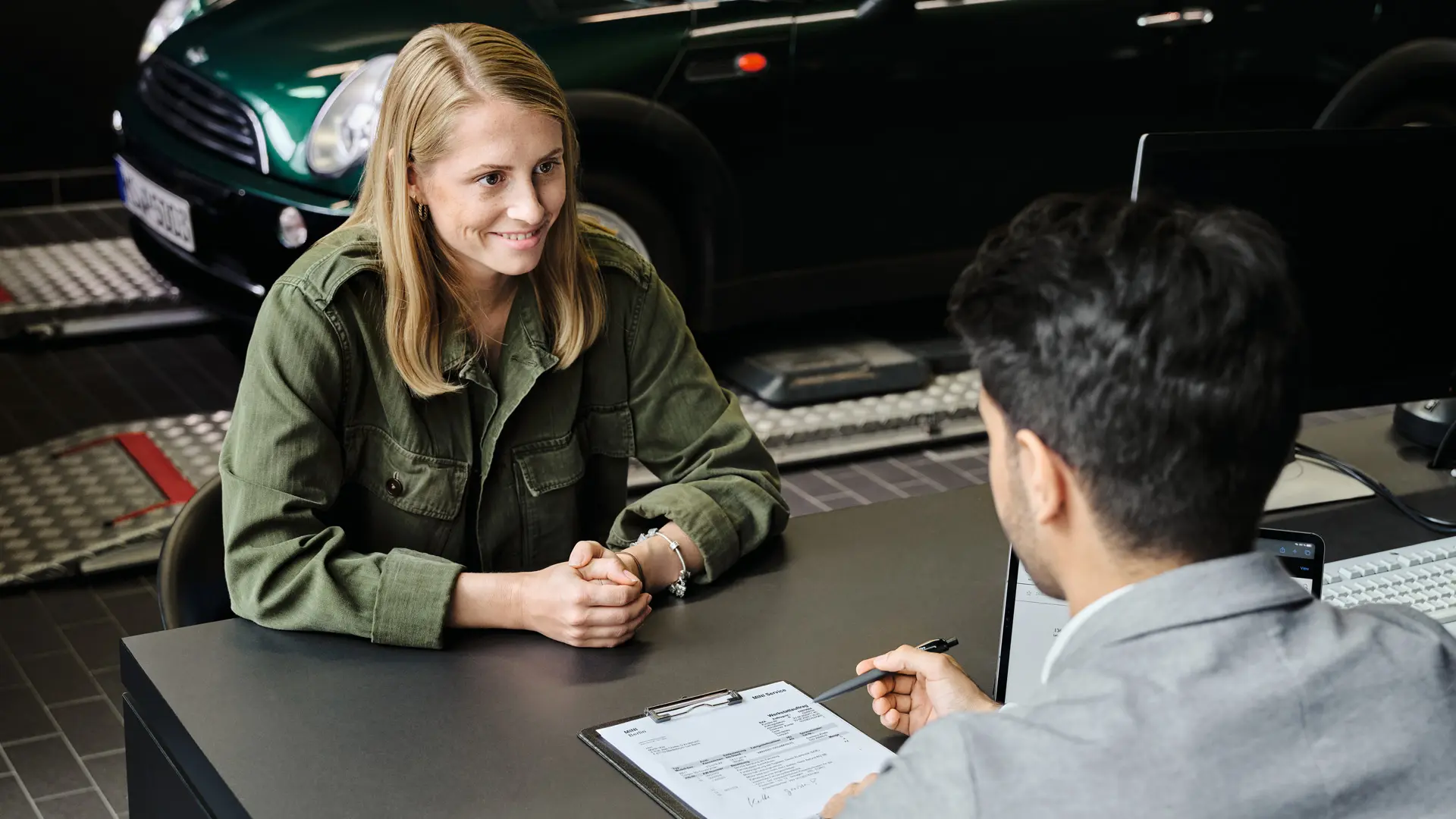 Ein Berater informiert eine Kundin bei einem MINI Partner an einem Tisch über die Serviceoptionen.