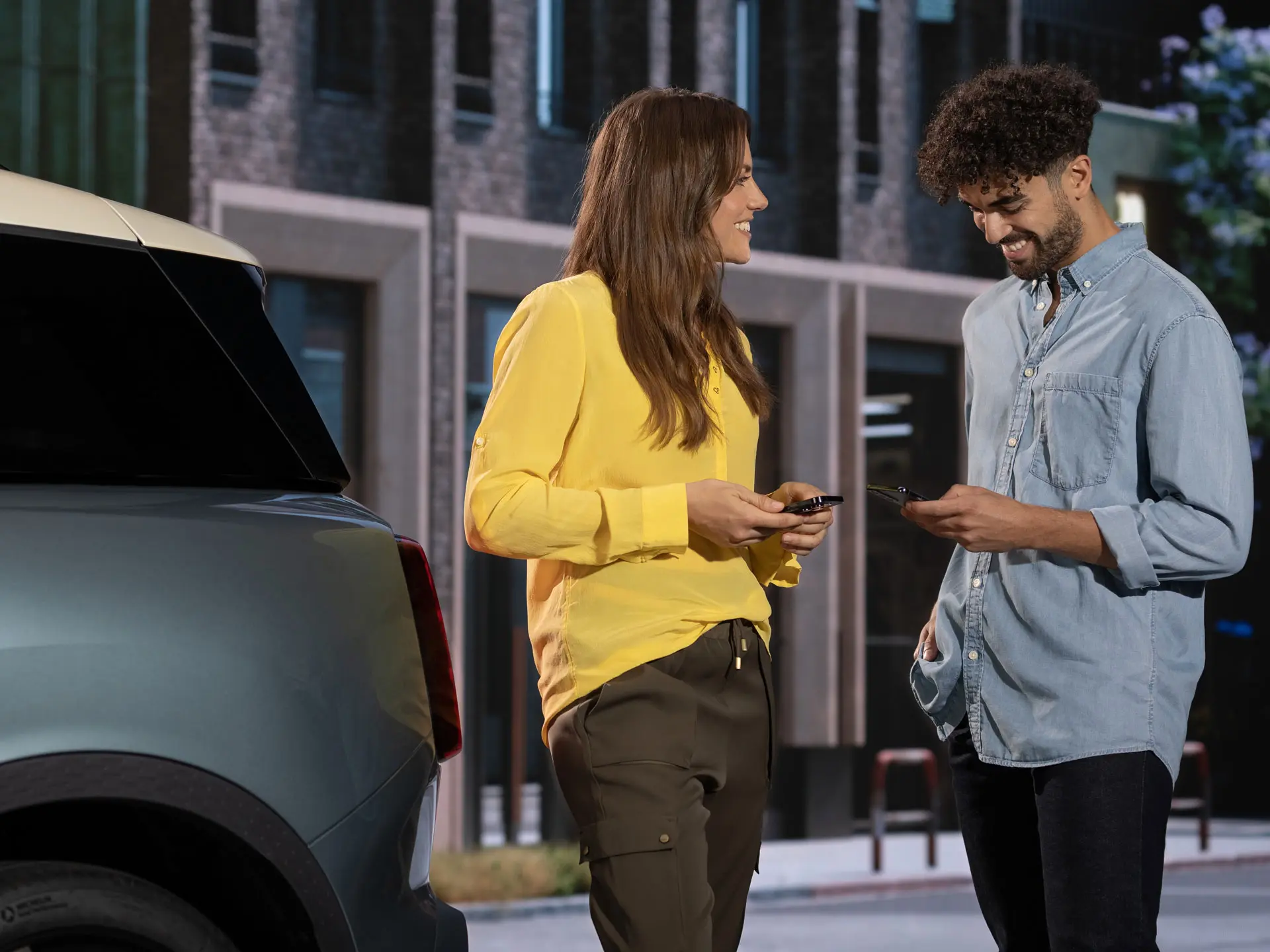 Mann und Frau stehen neben einem MINI  und kontaktieren einen MINI Service Partner mit ihren Handys.