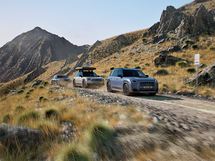 Bild von mehreren MINI Countryman Untamed Edition-Modellen, die auf einer Bergstraße im Gelände fahren.
