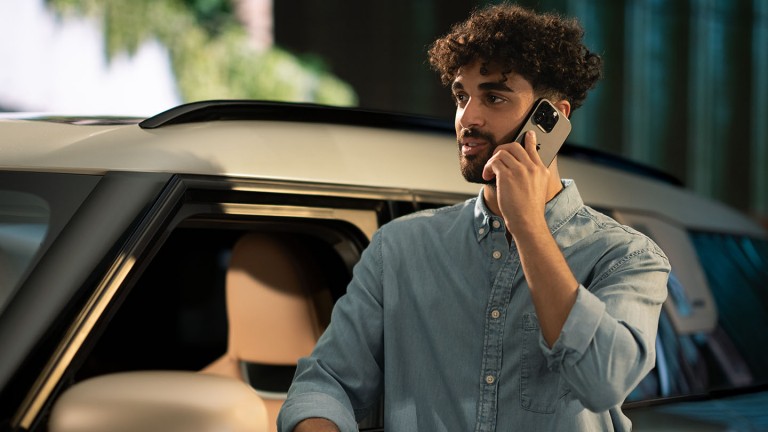 Ein junger Mann steht neben einem MINI Countryman und telefoniert