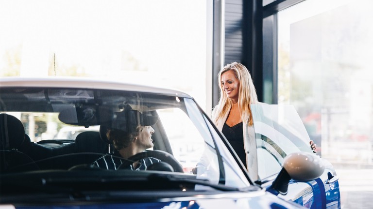 Eine Frau sitzt in einem MINI mit geöffneter Türe und spricht mit einer Verkäuferin